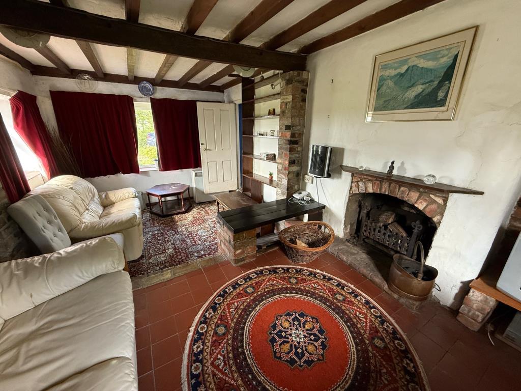 Lot: 120 - DETACHED COTTAGE IN MID-ESSEX VILLAGE LOCATION WITH POTENTIAL - Split level living room with fireplace